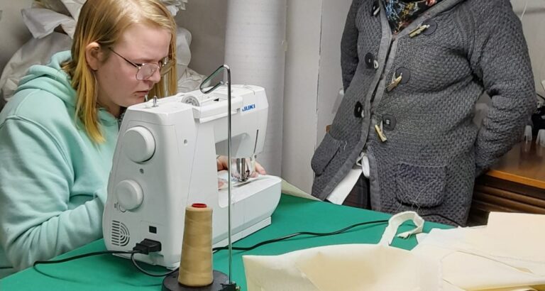 a woman sewing and another woman next to her